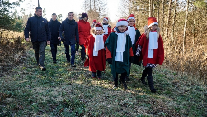 Cilvēki iet pa mežu