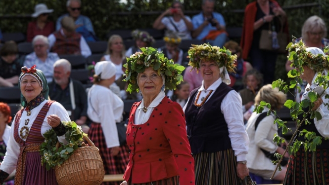Sievietes ģērbtas tautas tērpos un ziedu vainagi galvā