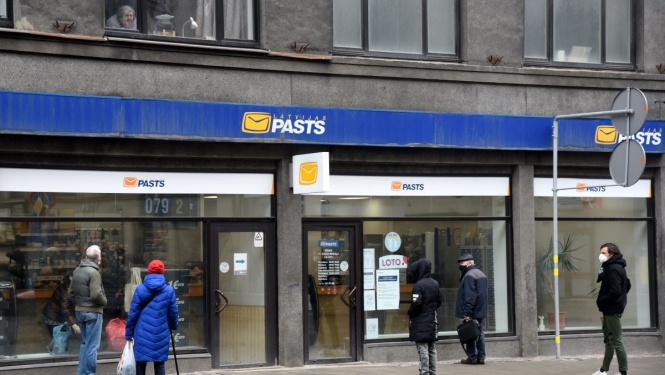 Cilvēki stāv rindā pie Latvijas pasta