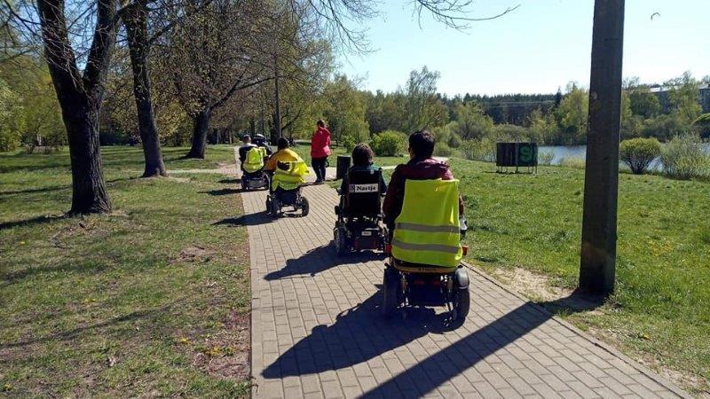 Cilvēki ratiņkrēslos pastaigā