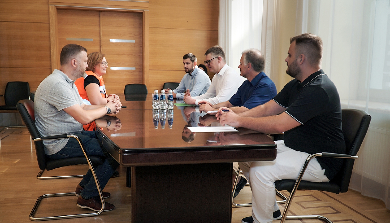 Cilvēki sēž sapulcē pie galda