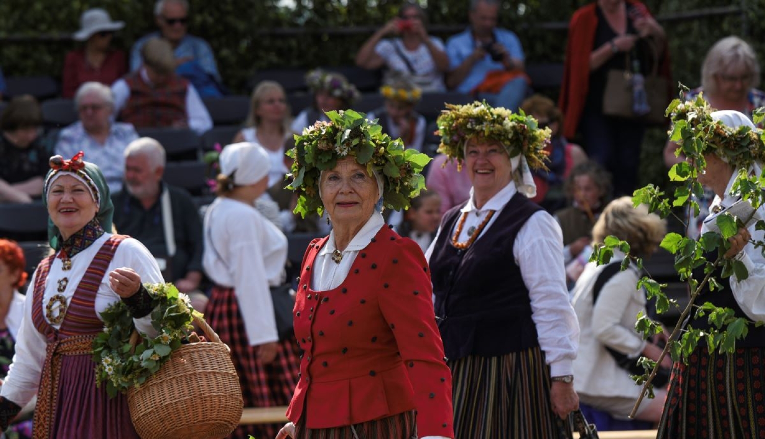 Sievietes ģērbtas tautas tērpos un ziedu vainagi galvā