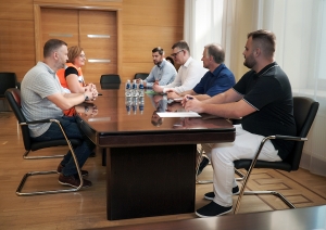 Cilvēki sēž sapulcē pie galda