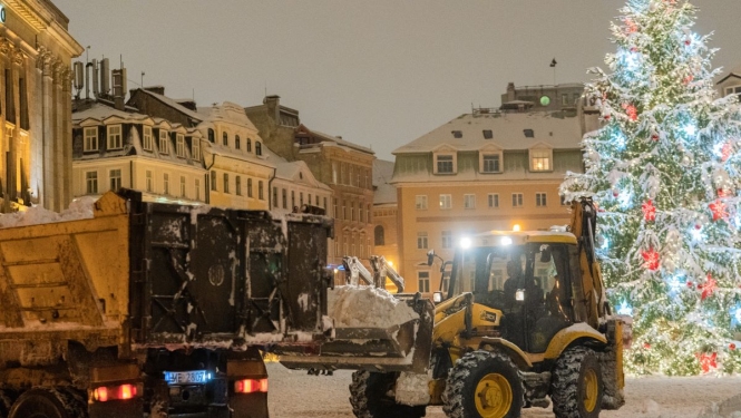 Traktors kravas mašīnā krauj sniegu